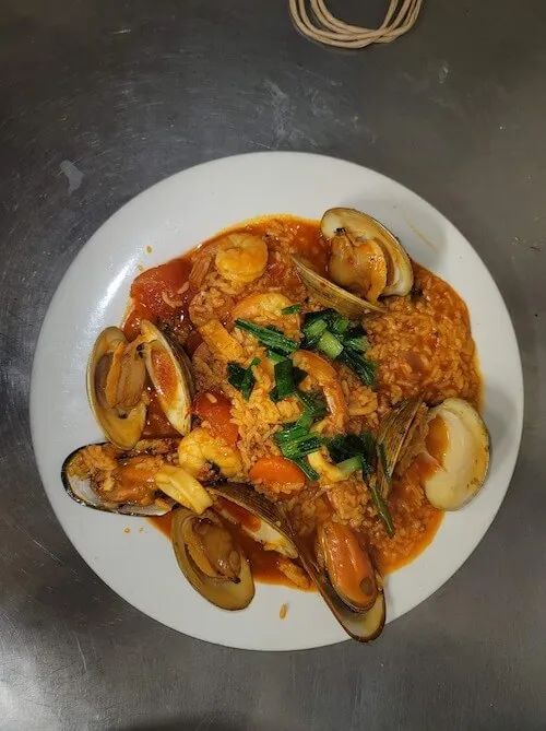 Mussels and clams in red sauce with herbs on a white plate