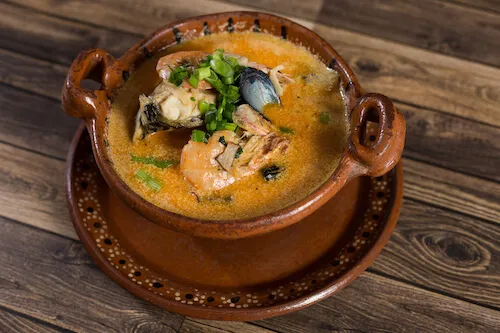 Seafood soup in a clay pot topped with cilantro