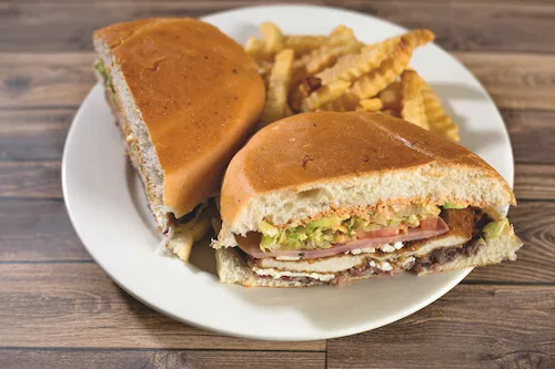 Two halves of a torta with fries on a white plate