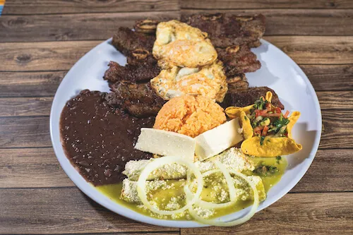 Mixed grill platter with skewers, cheese, nopales and onions beside black beans