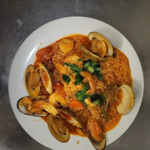 Mussels and clams in red sauce with herbs on a white plate