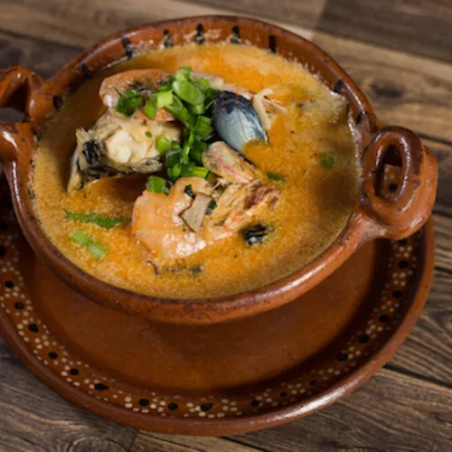 Seafood soup in a clay pot topped with cilantro