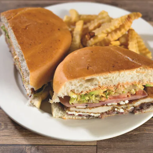 Two halves of a torta with fries on a white plate