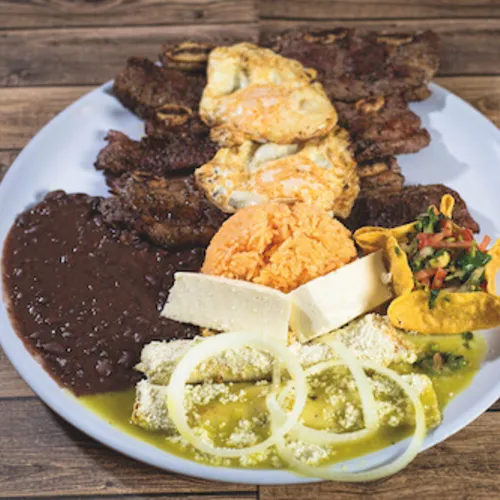 Mixed grill platter with skewers, cheese, nopales and onions beside black beans
